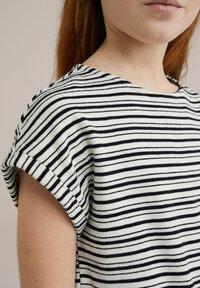 Prašna kratkodlaka majica z ribasto teksturo, črno-bele horizontalne črte in zaobljenim izrezom z zvitimi manšetami.