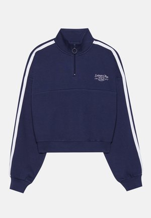 Navy blue cropped sweatshirt with a high collar, white side stripes, front zipper, and printed logo on the chest. Soft fabric.