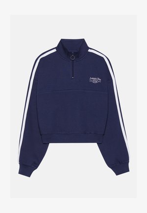 Felpa cropped blu navy con colletto alto, strisce bianche sui lati, zip frontale e logo stampato sul petto. Tessuto morbido.