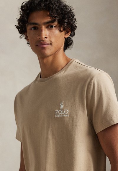 Μπεζ βαμβακερό t-shirt με στρογγυλή λαιμόκοψη, με μικρό κεντημένο λογότυπο "Polo Ralph Lauren" σε λευκό. Κοντά μανίκια και λεία υφή.