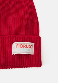Red knitted beanie with a ribbed texture. Features a branded tag with "Fiorucci Milano" in red and blue on a white background.