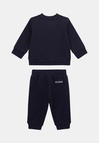 Mørkeblå genser med rund hals og matchende joggebukser for småbarn, med "GUESS" logo brodert på lommen til joggebuksene.
