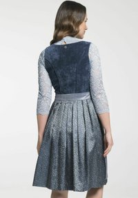 Blauwe jurk met patroon, voorzien van kantdriekwartmouwen, een fluwelen lijfje en een geplooide rok. Heeft een satijnen tailleband en een sluiting met knopen aan de achterkant.