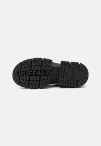 Crna gumena potplat tenisice s dubokim uzorcima. Sadrži istaknuti natpis "BUFFALO" u reljefu, uz teksturirane naglaske blizu pete.