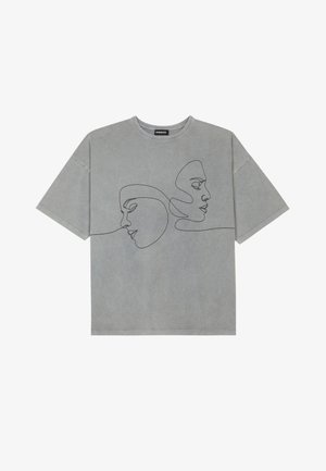 T-shirt en coton gris à manches courtes, présentant un dessin minimaliste en ligne noire de deux visages sur le devant, un col rond et une coupe décontractée.