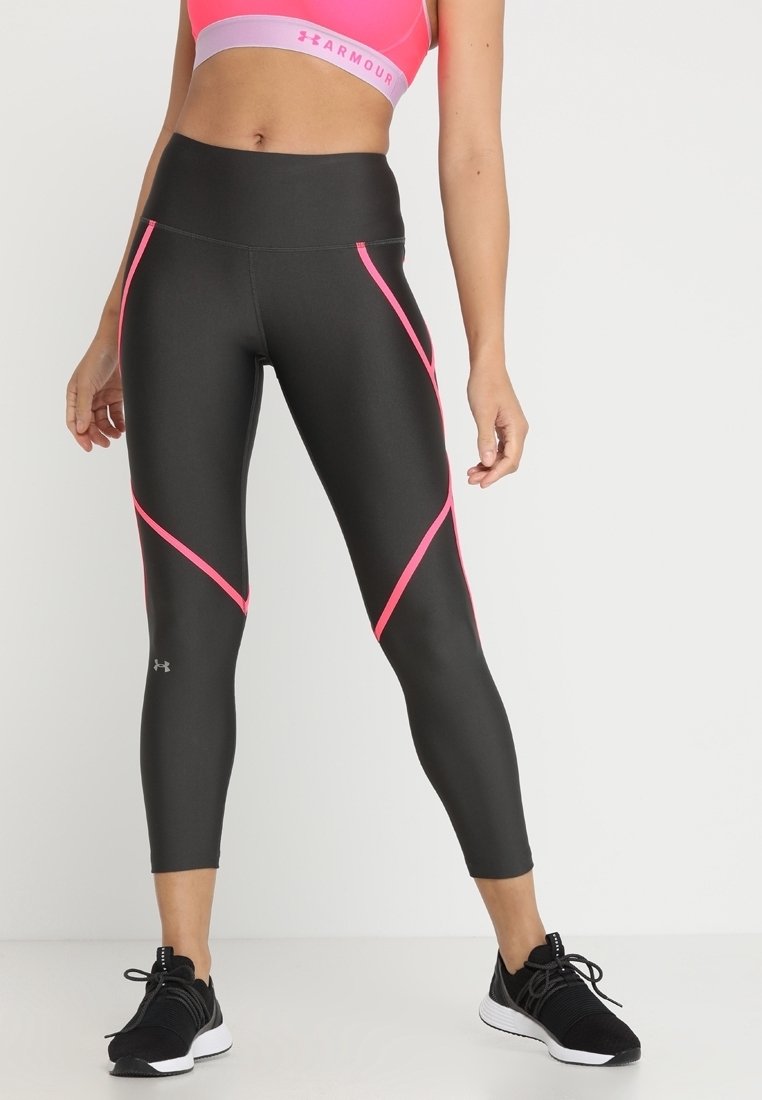 Leggings noirs avec des accents diagonaux roses, taille haute, fabriqués en matériau extensible, assortis à des chaussures de sport noires.