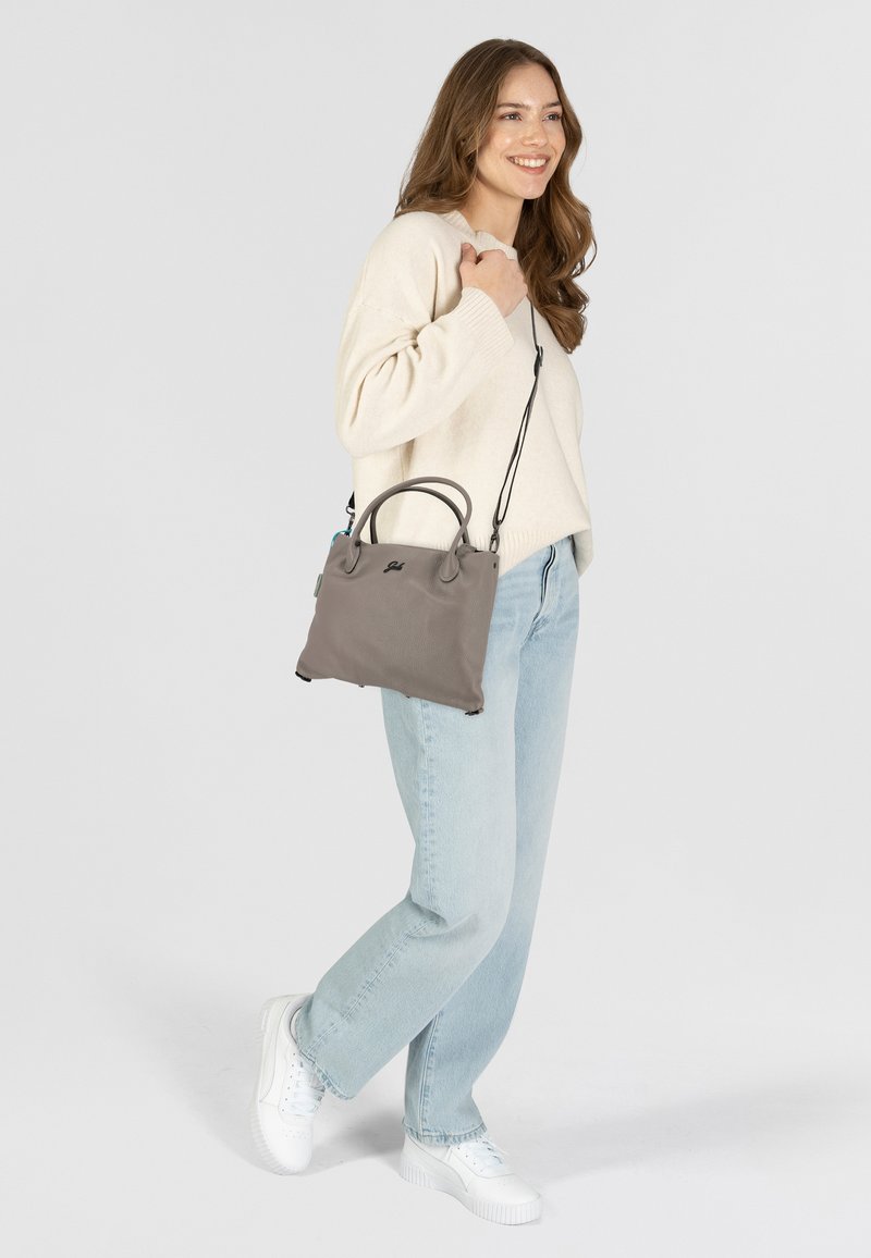 Graue Lederhandtasche mit zwei Obergriffen und einem abnehmbaren Schulterriemen, mit einer glatten Textur und subtiler Markenkennzeichnung auf der Vorderseite.