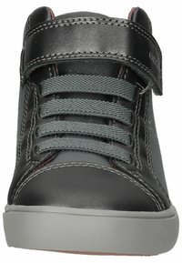 Zapatilla alta de cuero negro con acentos de tela gris, que cuenta con una correa de velcro, cordones grises y una suela de goma gris clara.