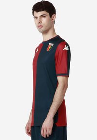 Tričko s krátkym rukávom na futbal v tmavomodrej a marónovej farbe, s emblémom leva, kruhovým výstrihom a logom Kappa na oboch rukávoch.