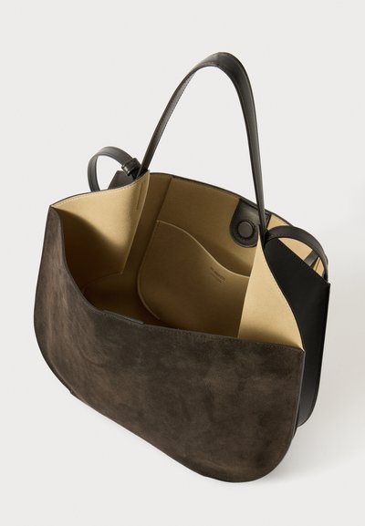 Borsa a tote in suede marrone con un accento in pelle nera liscia, un interno aperto dotato di una fodera beige e tasche laterali per l'organizzazione.