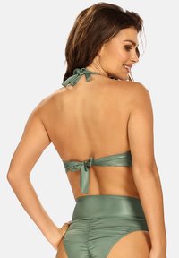 Jasnozielony bikini z wiązaniem na szyi i wysoko osadzonym dołem. Gładki, błyszczący materiał z marszczoną teksturą z tyłu.