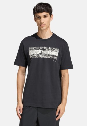 Junger Mann mit kurzen dunklen Haaren, der ein schwarzes T-Shirt mit weißer Grafik und dem Text "Every Day Counts" trägt, steht vor einem weißen Hintergrund.