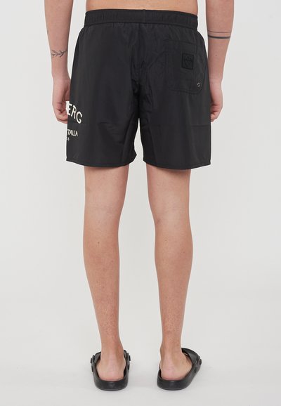 Pantaloni da nuoto neri con cintura elastica e tasca sul retro. Presentano un dettaglio con logo bianco sul lato sinistro. Tessuto liscio, materiale leggero.