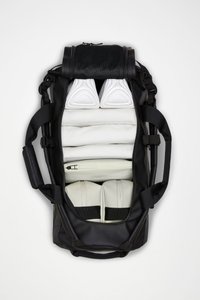 Sac de voyage noir avec plusieurs compartiments ; comprend un rembourrage blanc, une pochette zippée blanche et deux paires de chaussures blanches avec des accents noirs.