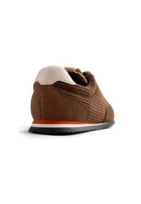 Baskets en daim marron avec un design perforé, capuchon de talon blanc et bande d'accent orange sur une semelle noire. Texture lisse et forme ronde.