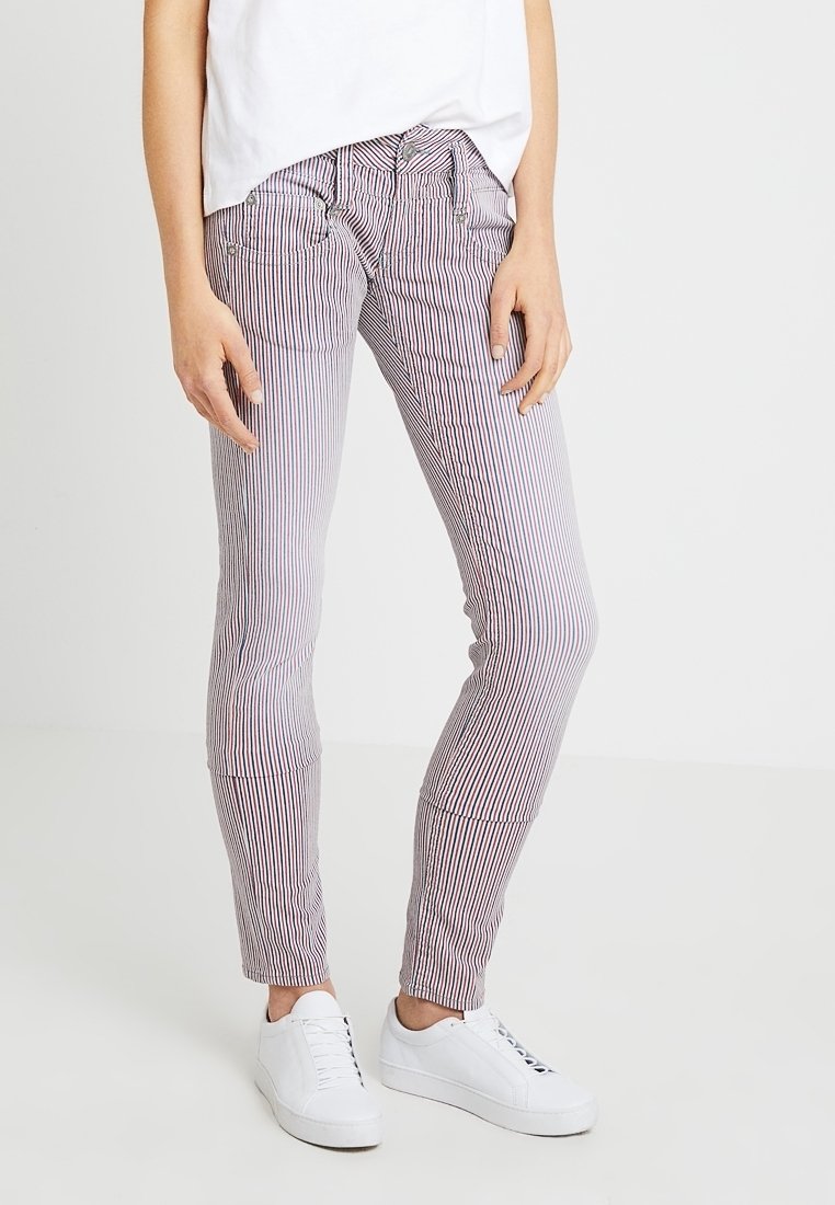 Randiga byxor i röd och vit tyg, slim fit med sidofickor och en synlig dragsko. Bärs med vita sneakers och en lös vit topp.