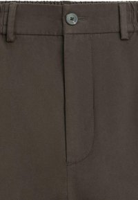 Pantaloni marroni leggeri con vita elastica, chiusura con bottone e tasca anteriore piatta. Tessuto liscio con dettagli di cuciture semplici.