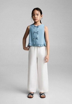 Top sans manches bleu clair avec des accents en nœud et un ourlet à volants, associé à un pantalon large blanc et des sandales navy. Design simple et épuré.