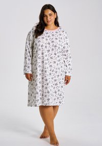 Biała koszula nocna z czarnym kwiatowym wzorem, długimi rękawami oraz różową lamówką przy kołnierzu, zaprojektowana z myślą o komforcie i swobodzie ruchów.