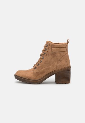 Bottines en daim marron avec un bout arrondi, un laçage à l'avant et un talon empilé. Elles disposent d'une languette de tirage et d'un col rembourré pour plus de confort.
