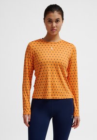 Lange mouwen sporttop in feloranje met zwart geometrisch patroon; heeft een ronde hals en een klein logo op de borst.