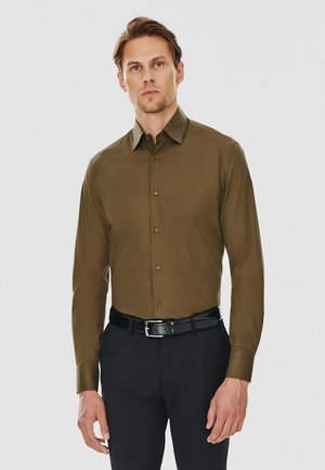 Olive green, długi rękaw, koszula zapinana na guziki, z ostro zakończonym kołnierzykiem, slim fit, z teksturowanej tkaniny, w połączeniu z ciemnymi spodniami i czarnym paskiem.