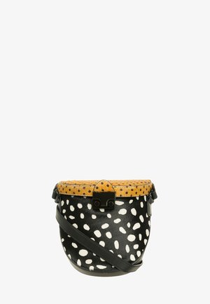 Round handbag featuring a black and white spotted pattern, tan top with black dots, and a black strap and hardware.