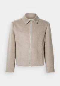 Jasnobeżowa kurtka na zamek z kołnierzem, wykonana z gładkiej, teksturowanej tkaniny, z subtelnymi haftowanymi akcentami na kołnierzu.