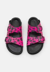 Rosa leopardmönstrade sandaler med svart sula och justerbara silverfärgade spännen. Har öppen tå och remmar över foten för en säker passform.