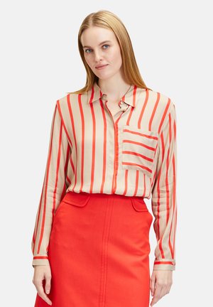 Beige blouse with red vertical stripes, long sleeves, collar, and chest pocket, paired with a bright red skirt. Smooth texture.