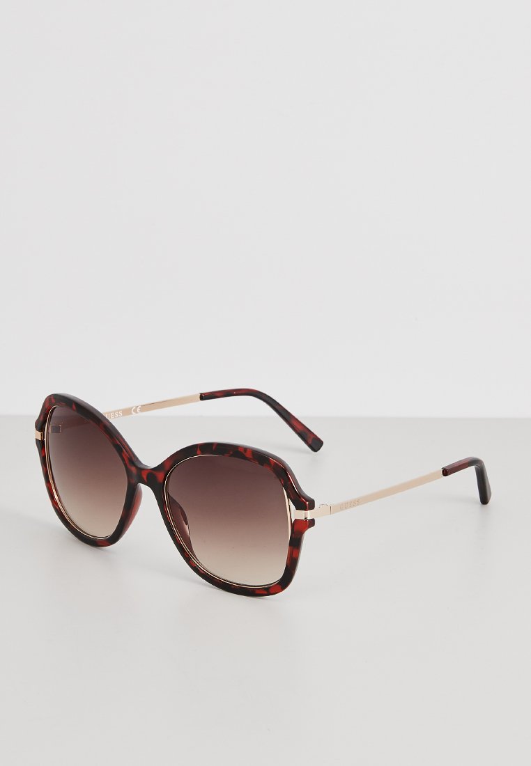 Brown tortoiseshell sunglasses with gradient lenses, oversized butterfly shape, gold-tone metal accents, and thick plastic frames.