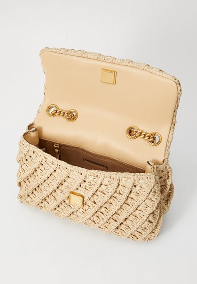 Vävd beige handväska med en strukturerad mönster, guld detaljer, och en enkel öppning med lock som avslöjar en slät insida.
