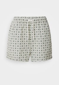 Short blanc avec un motif floral circulaire vert et noir et un cordon blanc à la taille élastique.