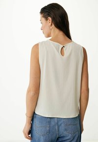 Lichtgrijze, mouwloze top met een gestructureerd oppervlak, voorzien van een sleutelgatdetail aan de achterkant, gestyled met hoge taille blauwe jeans.