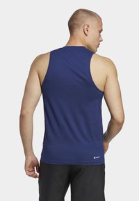 Sötétkék tank top, puha anyagból készült, kerek nyakkivágással és versenyháton, egyszerű logóval az alján.