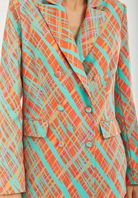 Double-breasted blazer in vibrant orange, teal, and pink plaid pattern. Features wide lapels, two front pockets, and matching buttons.