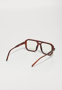 Gafas de marco cuadrado de carey marrón con lentes transparentes. Brazos delgados y curvados, y una línea de cejas prominente. Detalles metálicos en las bisagras.