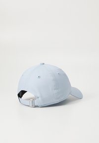 Light blue cotton baseball cap with a curved brim, adjustable strap at the back, and ventilation holes on the sides.