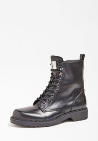 Bottines noires en cuir avec lacets, à bout rond, finition texturée, accents métalliques et semelle en caoutchouc robuste.