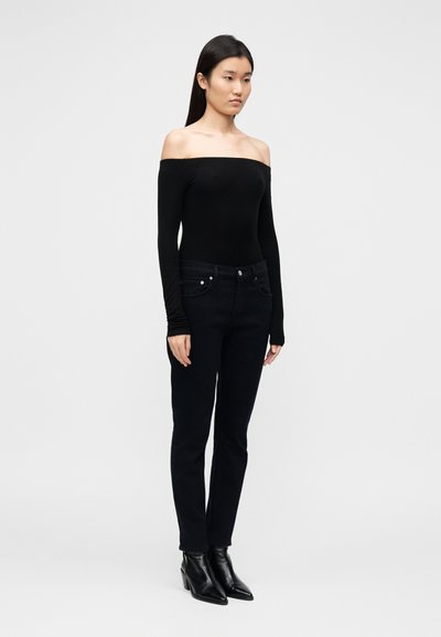 Black off-the-shoulder bodysuit with long sleeves, paired with dark denim jeans. The outfit features a fitted silhouette and ankle boots.