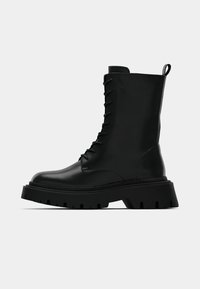 Black leather ankle boots with a rounded toe, lace-up front, and chunky rubber sole featuring deep treads. Textured matte finish.