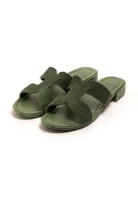 Sandalias verdes de diapositiva con correas texturizadas y en cruz, y un tacón bajo. Hechas de material flexible con un diseño de punta abierta.