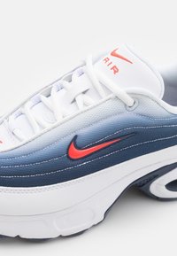 Scarpe Nike Air con design sfumato in azzurro e blu navy, tomaia sintetica bianca e logo con accenti rossi, dettagli in tessuto testurizzato.
