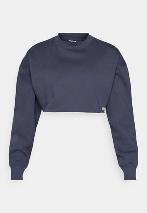 Avkortad mörkblå sweatshirt i bomull, med rund halsringning, långa ärmar och texturerad tyg med en diskret logotypetikett vid fållen.