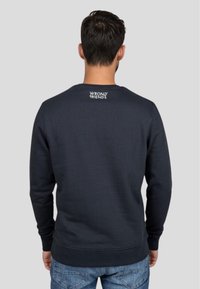 Sudadera de cuello redondo en azul marino con puños y dobladillo acanalados, que presenta un logo blanco de "WRONG FRIENDS" en la parte superior de la espalda. Fabricada con tela suave.