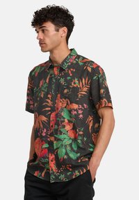 Kurzarmhemd aus dunklem Stoff mit lebhaftem Blumenmuster, das grüne Blätter und rot-orangene Blumen zeigt, mit Knopfverschluss und Taschenakzent.