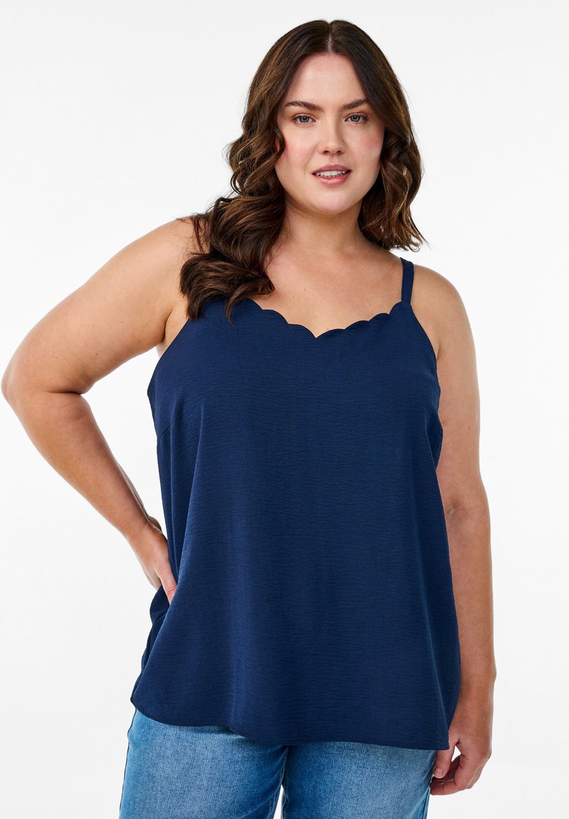 Top sin mangas de color azul marino con escote en forma de concha, fabricado en tejido ligero, de corte relajado, combinado con jeans de mezclilla azules.