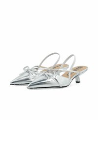 Talons slingback argentés avec un bout pointu, détail de nœud sur le dessus et un petit talon carré. Finition métallique lisse et semelles intérieures beige.