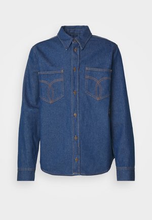 Tamsiai mėlynas džinsinis marškinis su smailiu apykakle, priekyje užsegamas mygtukais, dviem krūtininėmis kišenėmis ir kontrastingais oranžiniais siuvinėjimo detalėmis.