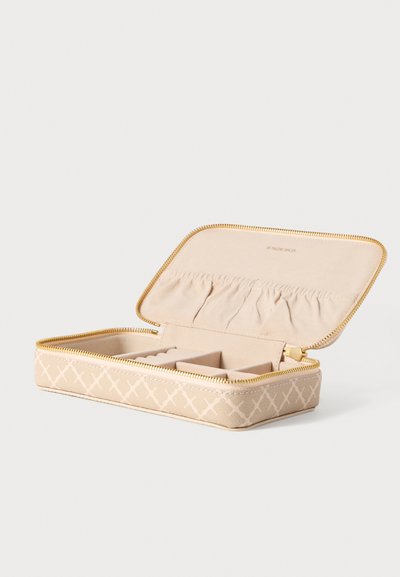 Μπεζ θήκη για κοσμήματα με σχέδιο σταυροβελονιάς, χρυστό φερμουάρ και μαλακό εσωτερικό. Διαθέτει διαμερίσματα για οργάνωση και θήκη για αποθήκευση.